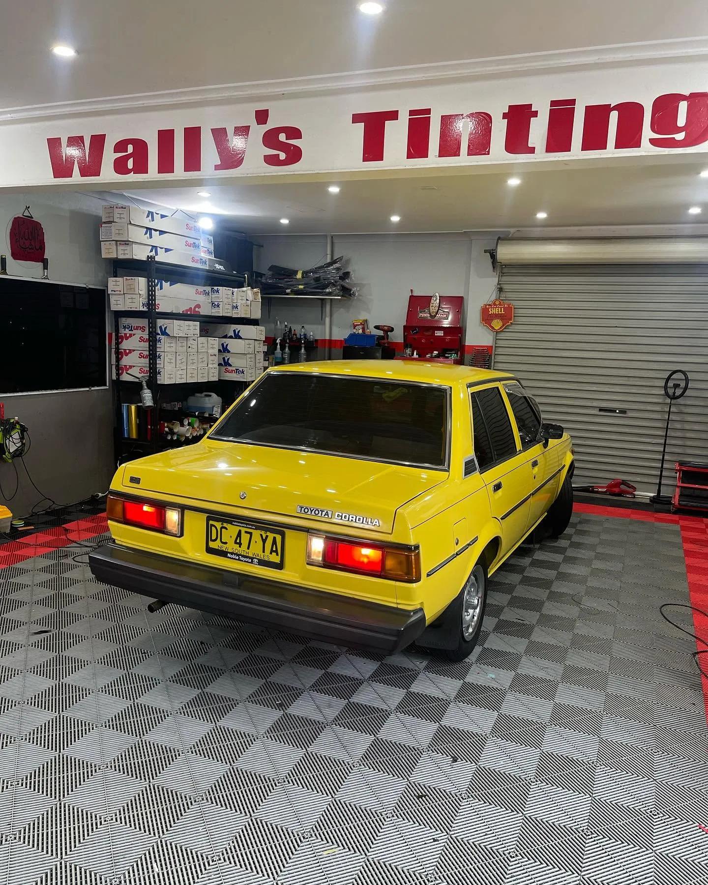 Yellow classic Toyota Corolla with tinted windows at Wally’s